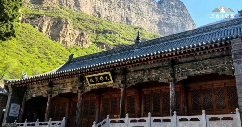 這座位於五台山的大羅宮古剎，依山勢而建，背靠陡峭的岩壁，展現出與大自然和諧共存的景象。寺廟的木製建築結構古樸莊重，門額上題有「大羅寶殿」，象徵著佛教的深遠智慧與修行之地。拾級而上的石階和精緻雕刻的白色欄杆，增添了莊嚴肅穆的氛圍，使來訪者在步入寺院前便能感受到內心的寧靜與敬畏。這座千年古剎不僅是佛教信仰的聖地，更是歷史與文化的寶藏，吸引著無數朝聖者與遊客前來參訪。