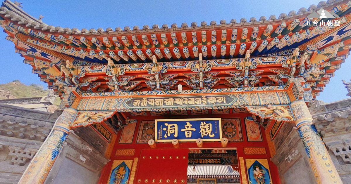 這張圖片展示了五台山觀音洞(Guanyin Cave)的山門,門額上書「觀音洞」,象徵此地供奉觀音菩薩,為信眾提供祈福與修行的場所。建築色彩鮮豔,雕刻細緻,融合了藏傳與漢傳佛教的藝術風格。上方的藏文咒語「唵嘛呢叭咪吽」是六字大明咒,代表觀音菩薩的慈悲加持。這裡是五台山著名的靈修勝地,吸引許多朝聖者前來參拜。