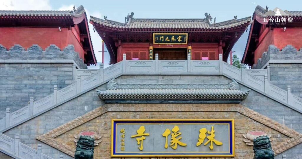 這座古剎以其壯觀的建築風格和深厚的宗教氛圍聞名。圖中可見金色匾額上刻有「殊像寺」的字樣，象徵著此地為文殊菩薩的道場。寺門兩側石獅守護，石階通往更高處的殿堂，展現出莊嚴神聖的氣息。這裡是許多信眾前來朝聖的重要地點，充滿虔敬與寧靜的氛圍。