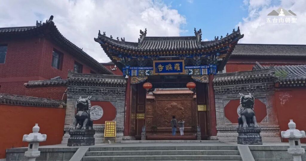 這張照片展示了五台山著名的羅睺寺(羅睺羅寺)正門,氣勢恢宏的山門以藍底金字匾額標示寺名。門口兩側矗立著石雕神獸,象徵守護寺院的威嚴。寺院建築保留了傳統的中式宮殿風格,紅牆灰瓦與精美雕刻相得益彰,展現出歷史的厚重感與宗教氛圍。這裡是朝聖者與遊客常駐的必訪之地,象徵著佛教文化的傳承與信仰的力量。