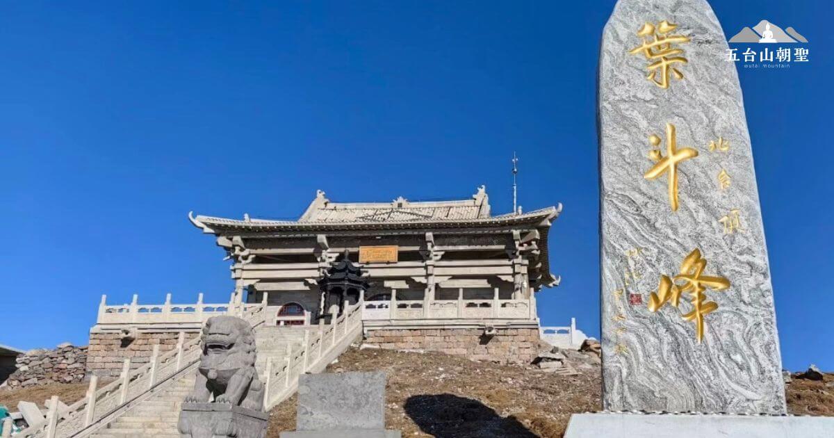 這張照片展示了五台山北台(葉鬥峰)的標誌性石碑,石碑上刻有「葉鬥峰」四個金色大字,象徵著北台在五台山五大主峰中的崇高地位。在石碑旁,一座古樸的寺廟矗立在山頂,階梯蜿蜒而上,兩旁有石獅守護,顯示出莊嚴肅穆的氛圍。藍天映襯下,整個景色更加壯麗,展現出佛教聖地的寧靜與神聖,這裡是許多信眾與登山者朝拜的重要地點。