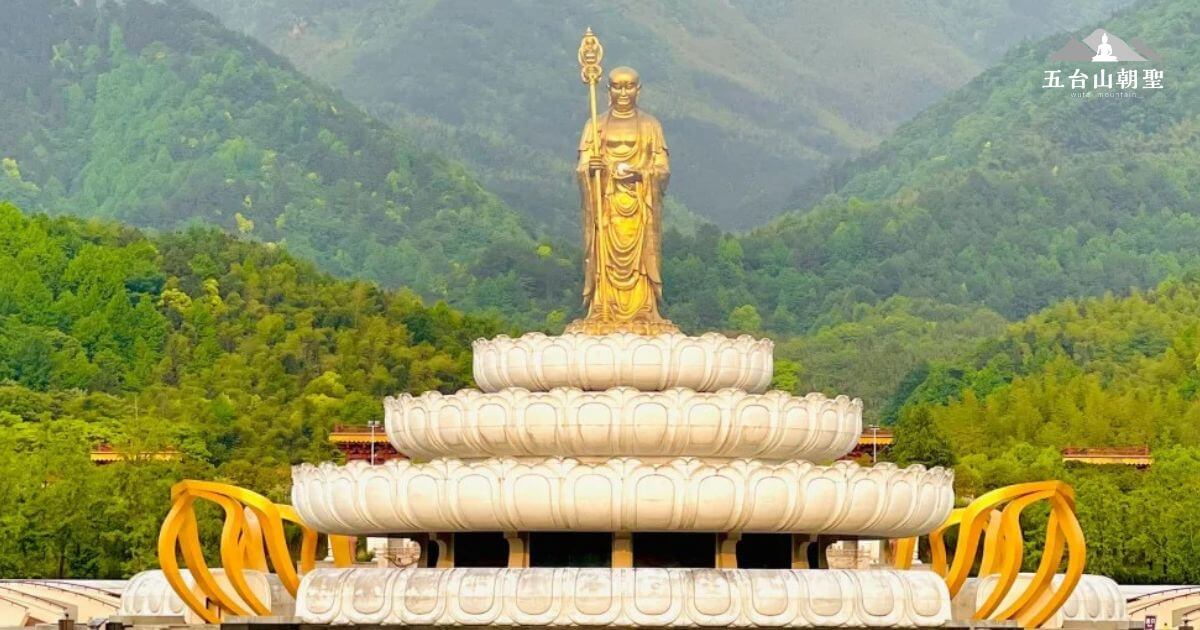 這張圖片展示了大園文化公園內一座壯麗的佛像，佛像高高矗立，站立在白色的蓮花座上，四周環繞著綠意盎然的山脈。背景的群山與佛像相映成趣，營造出一種和平與莊嚴的氛圍。這座金色的佛像象徵著智慧與慈悲，位於這片寧靜的自然景觀中，是大園文化公園的主要景觀之一，吸引了無數朝聖者與遊客來此參觀，感受內心的平靜與啟發。