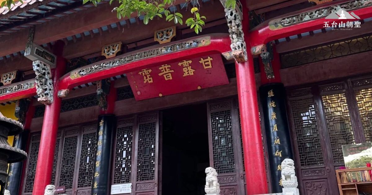 這張圖片展示了甘露寺（Ganlu Temple）的大門，兩側的紅色支柱和精緻的雕刻令人印象深刻。門口上方寫著「甘露」兩字，象徵寺廟的神聖與安寧。大門兩側的對聯和石獅增添了傳統文化的氛圍，為這座古老的寺廟增添了神秘與莊嚴的氛圍。這裡的景觀不僅是宗教信仰的中心，也是吸引遊客探索中國歷史與文化的重要景點。