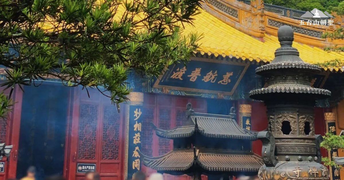 這張圖片展示了惠濟寺的建築與周圍的景觀。寺廟的屋頂覆蓋著金黃色的瓦片，營造出古色古香的氛圍。大殿前的香爐冒著煙霧，香火鼎盛，吸引著無數的信眾前來祈求。煙霧繚繞中，樹枝的綠意與古老的建築交織，營造出一種平和、神聖的氛圍。