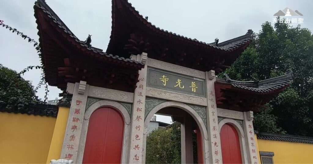 此圖片展示了普光寺的山門，建築風格古樸典雅，帶有傳統中式寺廟的特徵。石門上刻有「普光寺」三字，兩側對聯寫著與佛法與修行相關的詩句。寺門外環繞著綠樹，增添了一份寧靜與莊嚴的氛圍。普光寺是五台山眾多寺廟之一，吸引了許多信徒與旅人前來朝聖與參拜。