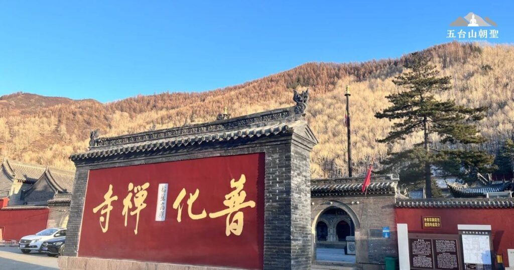 這張圖片展示了普化寺的雄偉大門，紅色牆面上用金字書寫的“寺禪化善”格外引人注目。寺廟的大門背後是壯麗的山脈，顯示出寺廟所處的自然環境與它的古老歷史相融合。山林背景的自然景色與古建築相互映襯，顯得寧靜又神聖，象徵著佛教文化的深厚底蘊。