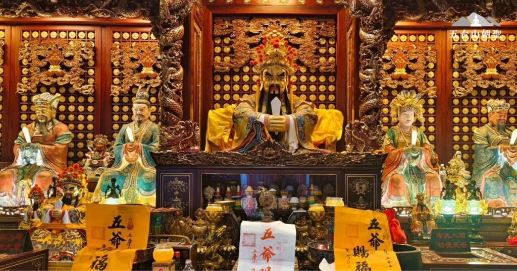這張照片展示了五台山著名的五爺廟內部,供奉著五爺(關聖帝君)以及其他神明,周圍裝飾華麗,雕刻精緻,充滿莊嚴神聖的氛圍。信徒們前來敬香祈福,祈求平安、財運與智慧,展現了五台山佛教與民間信仰交融的特色。